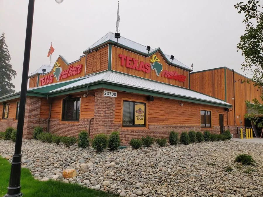 A texas roadhouse restaurant is surrounded by rocks and grass.