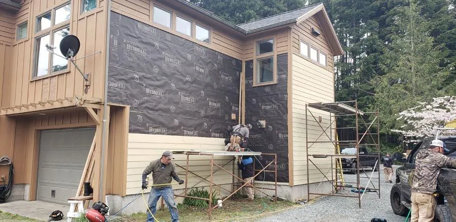 A group of people are working on the side of a house.